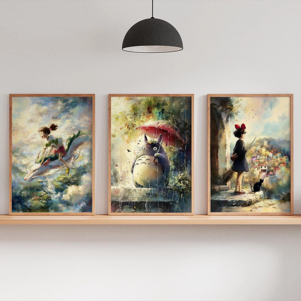 Three framed artworks on a wall shelf with a lamp and plants in the background.