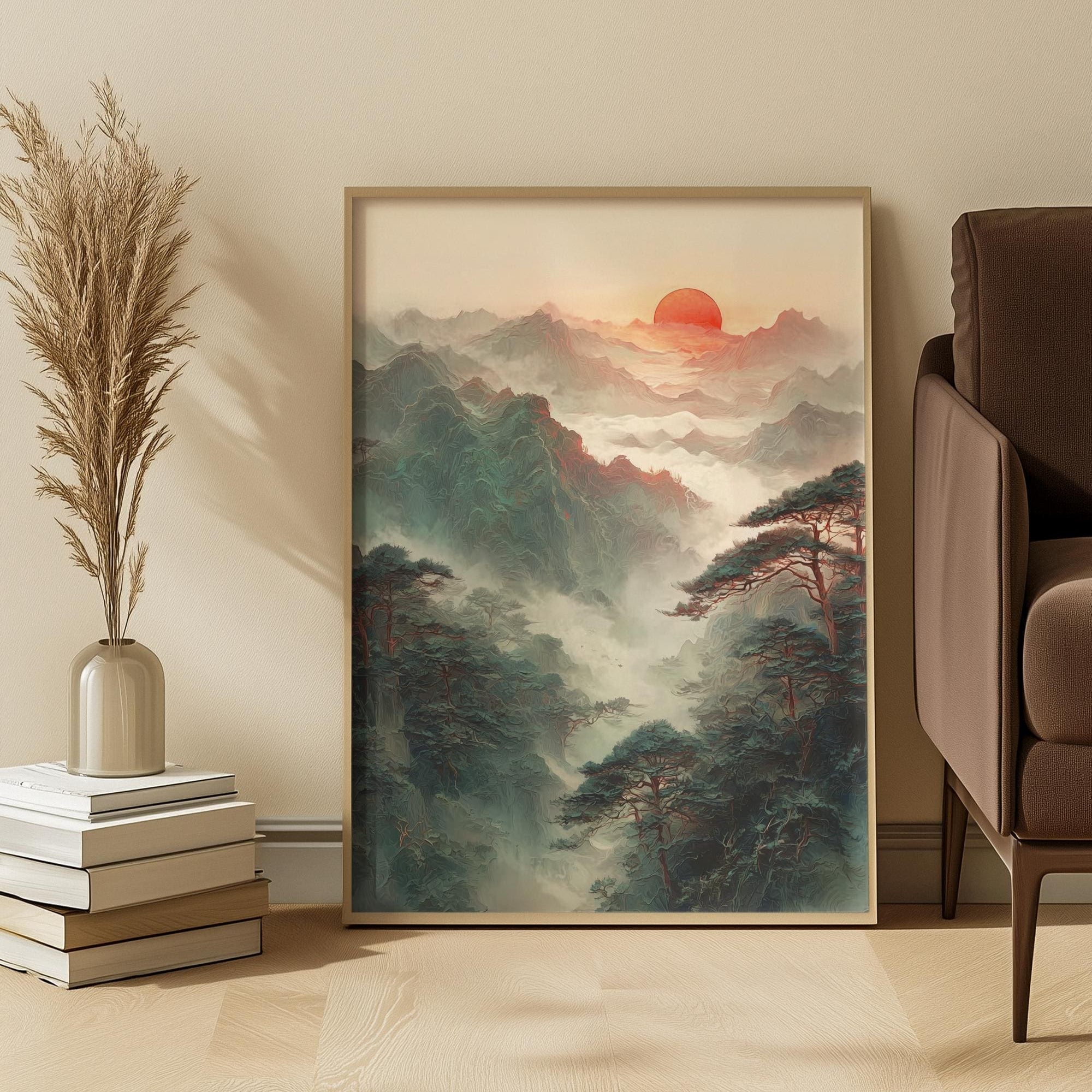 Framed artwork of a mountain landscape with a sunset, placed on a wall above a sofa and books.