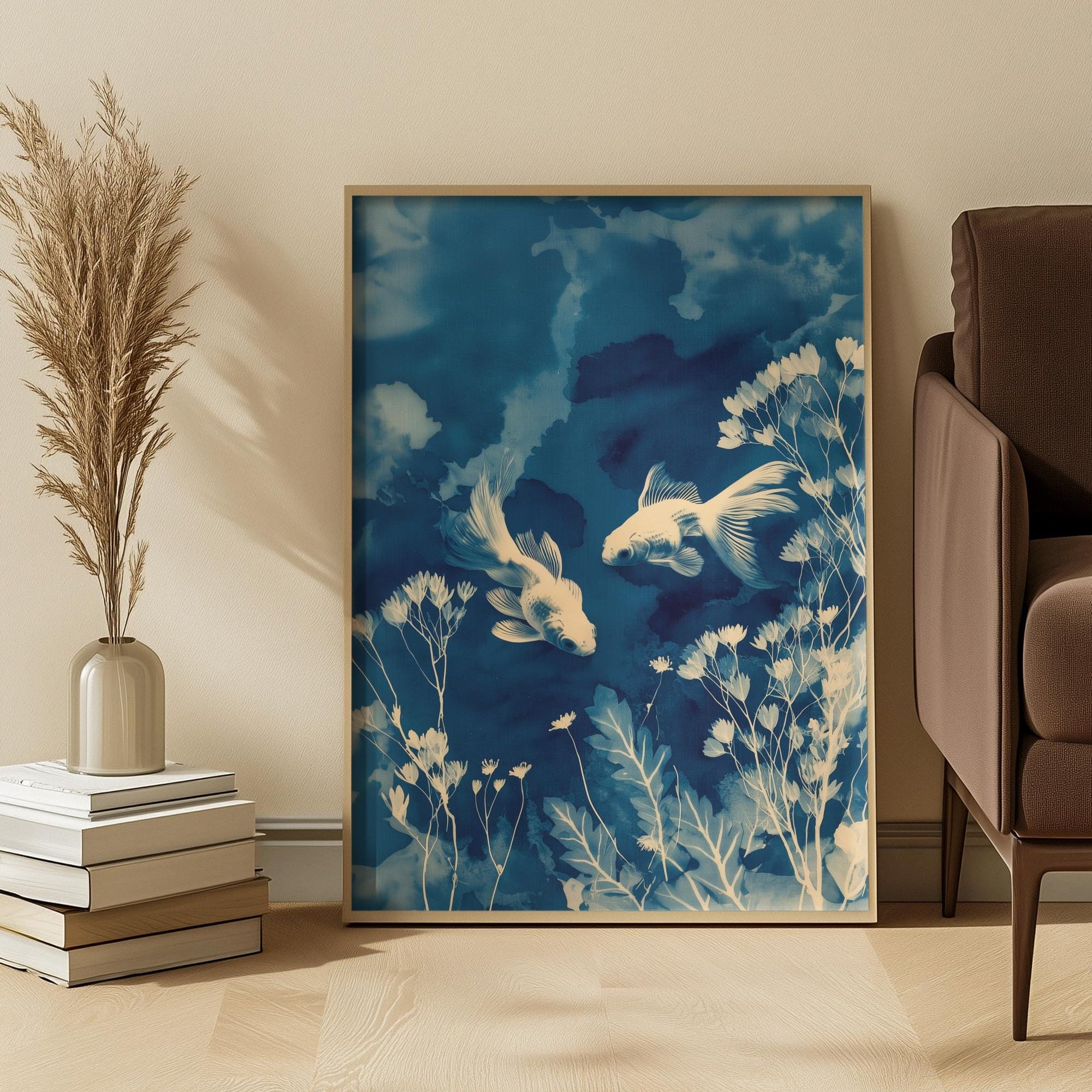 Framed artwork of Cyanotype goldfish and plants on a wall in a room with a chair and books.