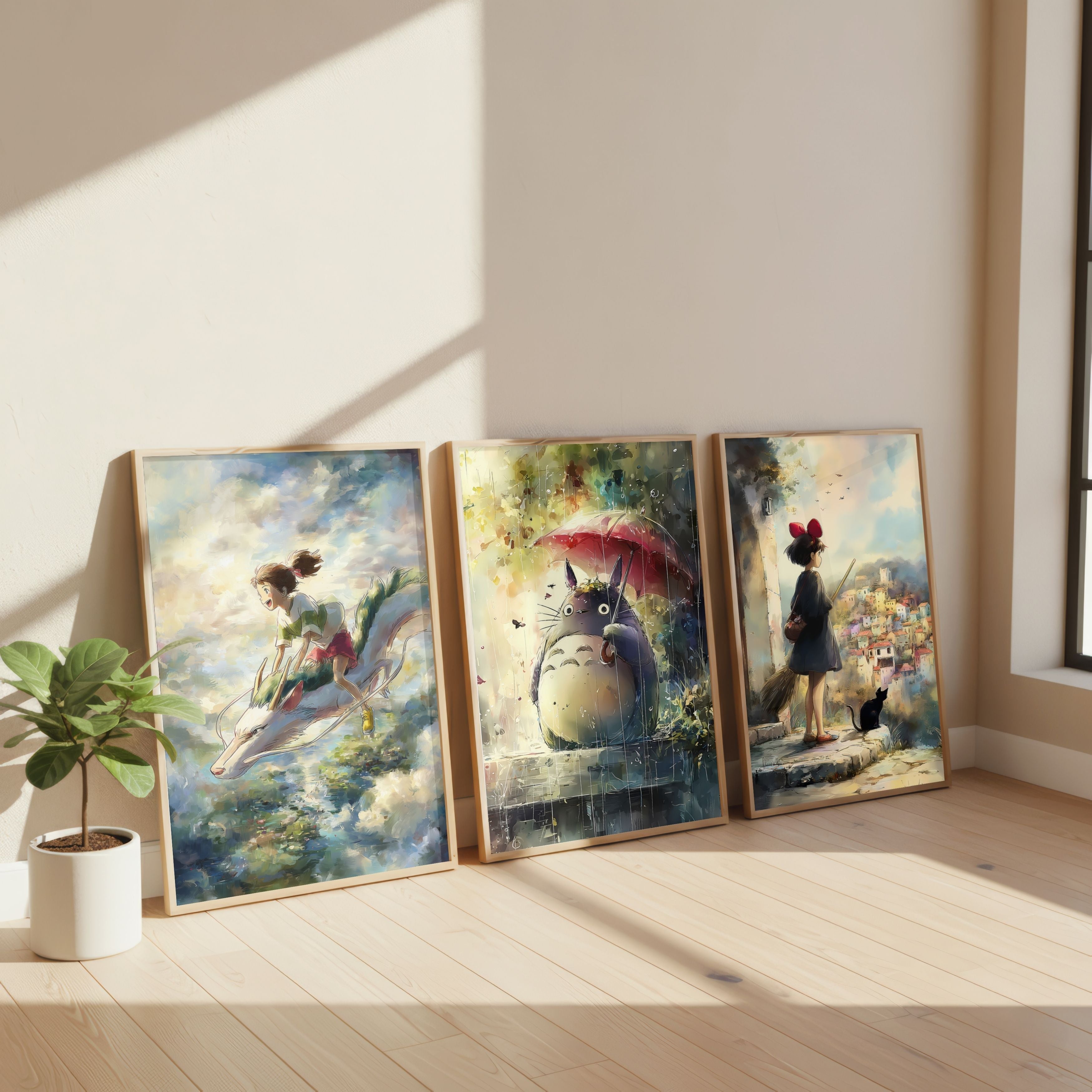 Three framed art prints featuring anime characters from Spirited Away, My Neighbor Totoro, and Kiki’s Delivery Service in a fantasy displayed side-by-side on a light wood floor against a beige wall with natural sunlight casting shadows.