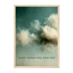 A framed art print featuring a textured teal and cream sky with the text 'GOOD THINGS WILL FIND YOU' at the bottom, enclosed in a light natural wood frame.