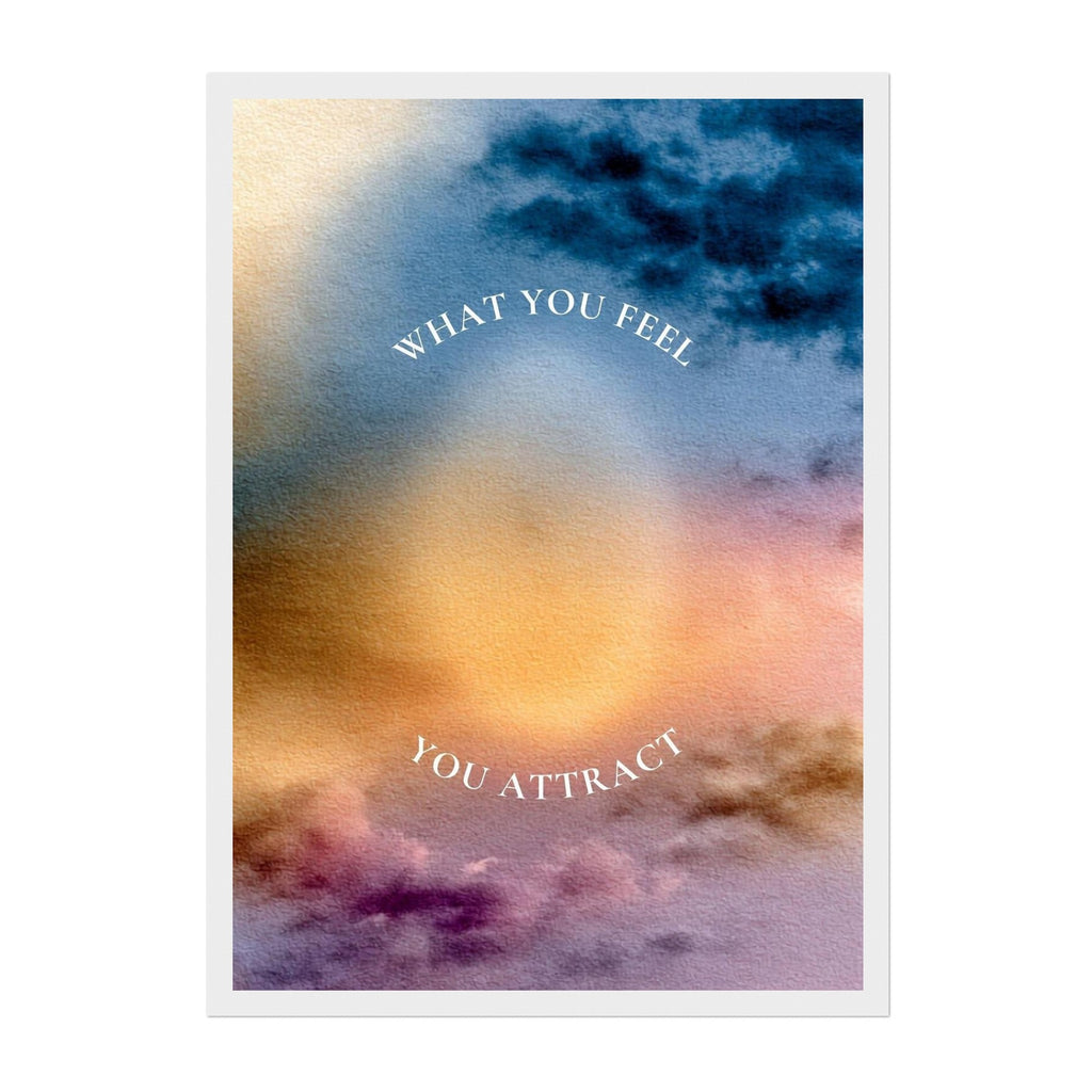 A square art print with a white border featuring an abstract watercolor sky design in blue, gold, orange, and purple hues, with the text 'WHAT YOU FEEL YOU ATTRACT' arched in white lettering.