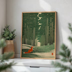A framed art print featuring a fox in a forest, styled on a white shelf next to a potted plant in a bright room.