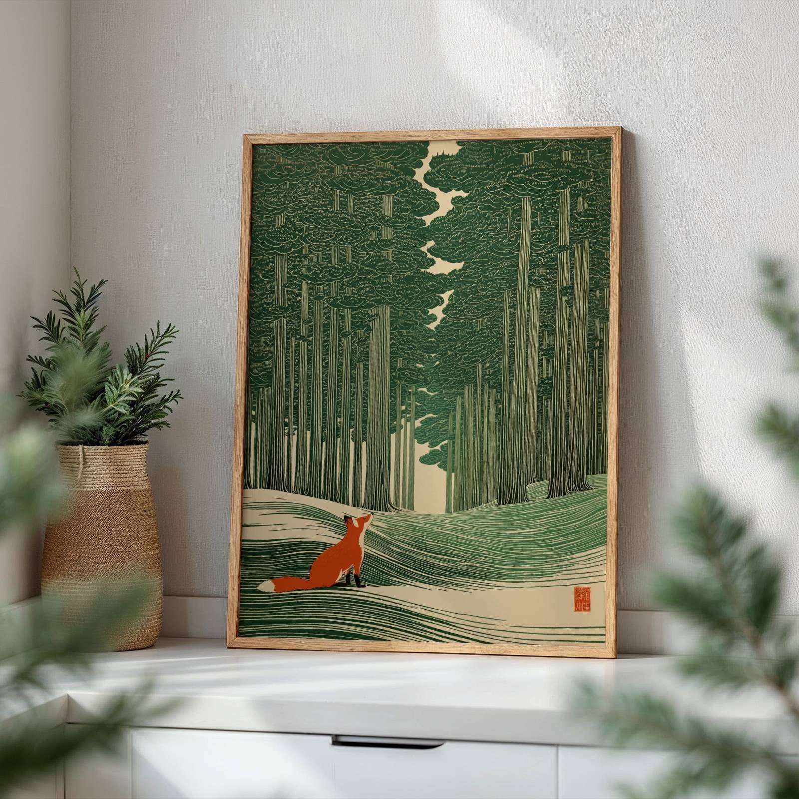 A framed art print featuring a fox in a forest, styled on a white shelf next to a potted plant in a bright room.