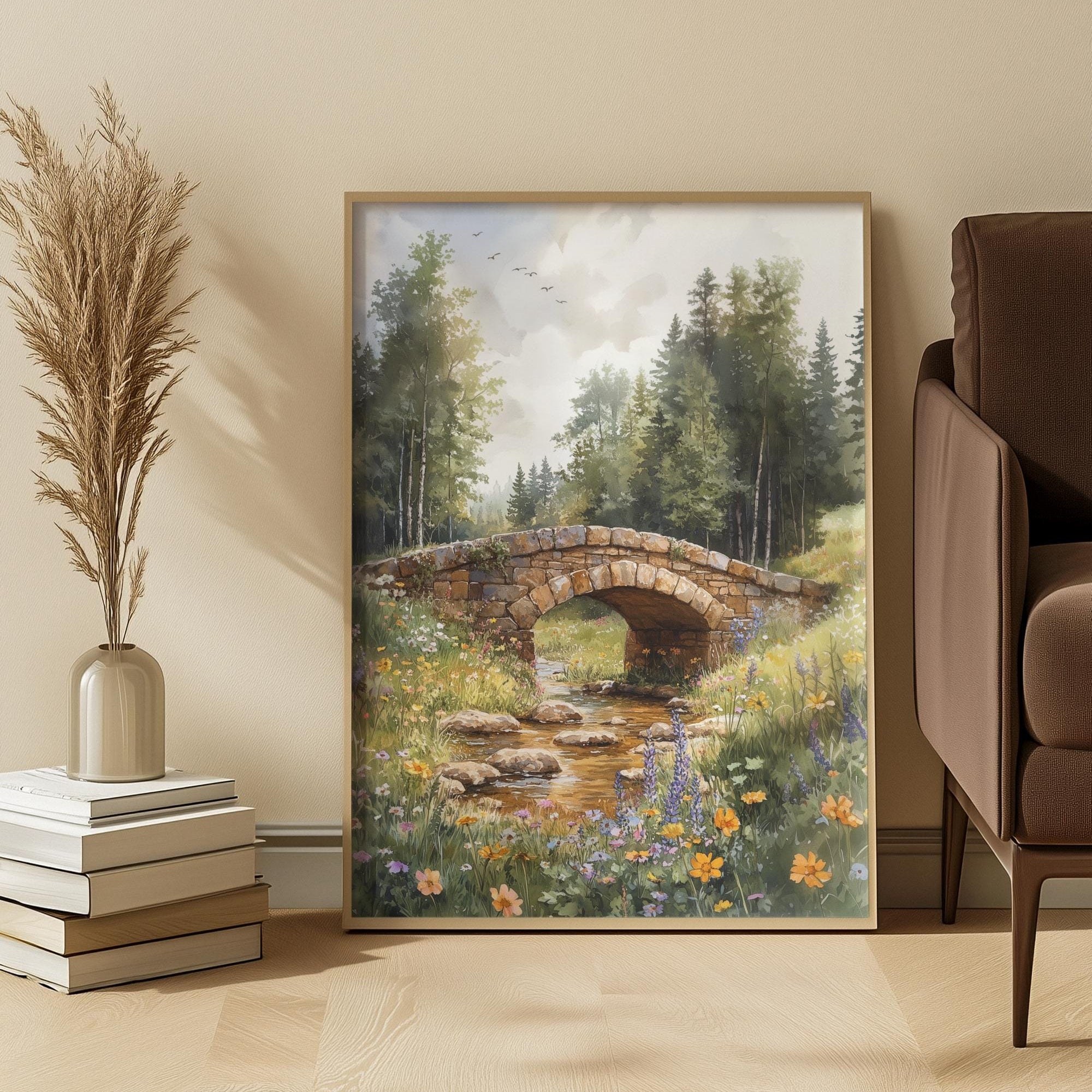 Framed nature painting of a meadow with a bridge over a stream in a room with decor elements.