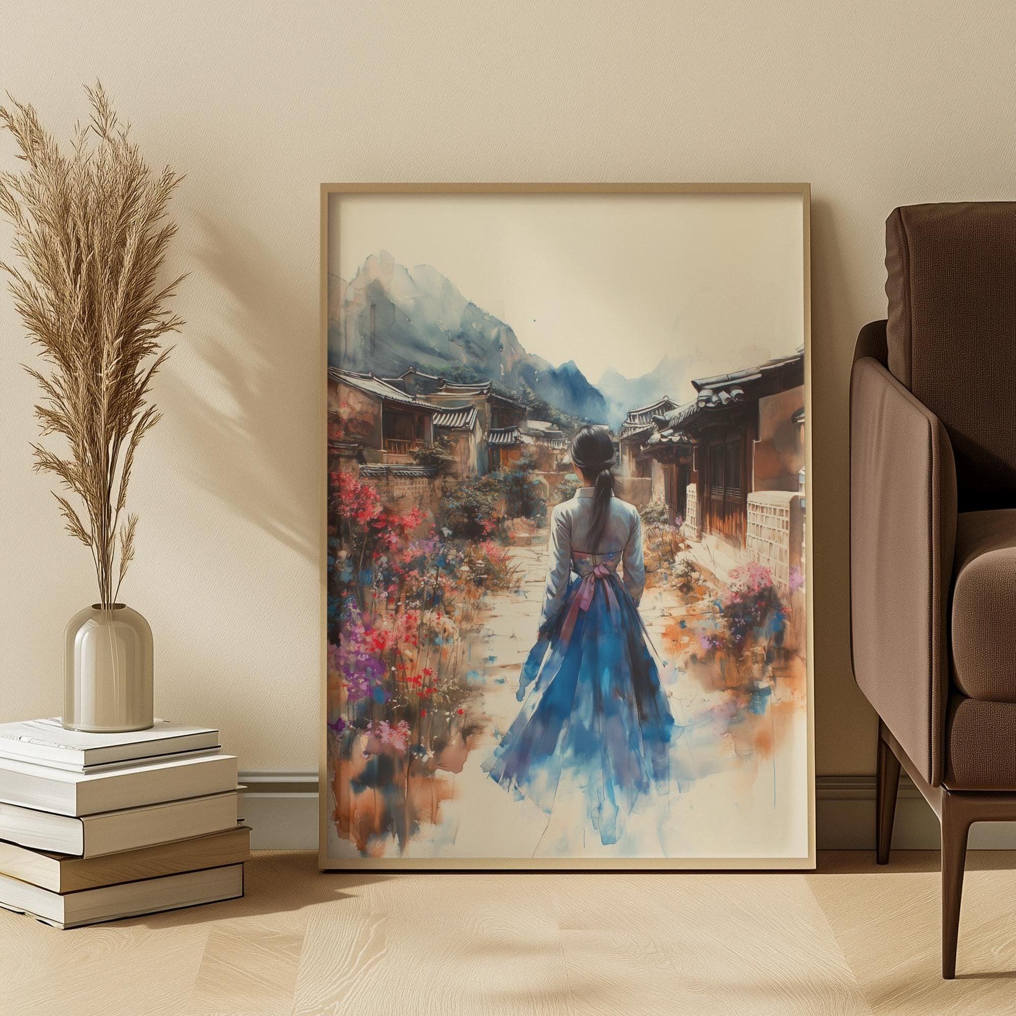Framed artwork of a korean woman in a blue hanbok walking through a village scene, placed on a wall in a room with a chair and decorative items.